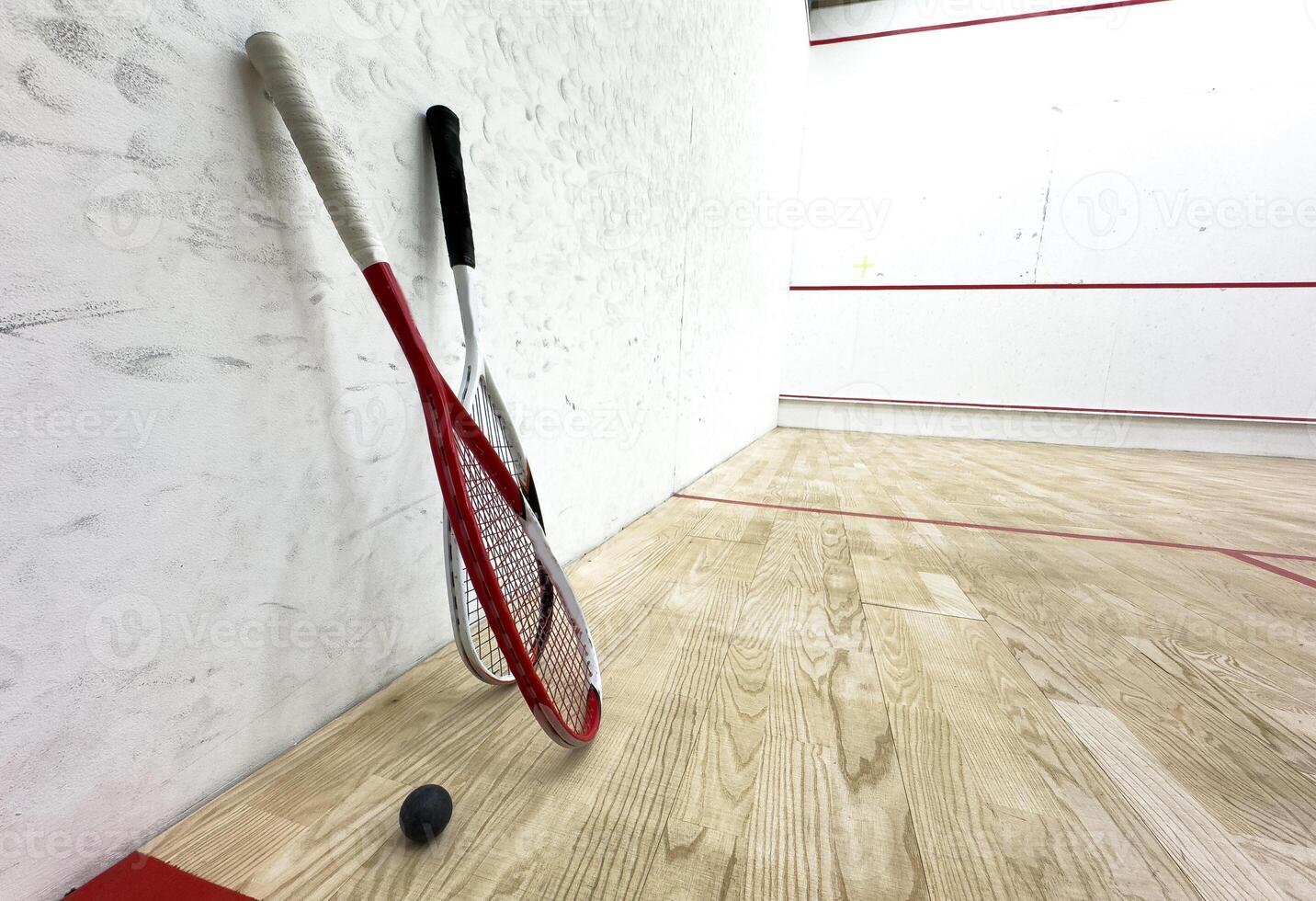 Two rackets and two squash balls lie on the parquet floor. photo