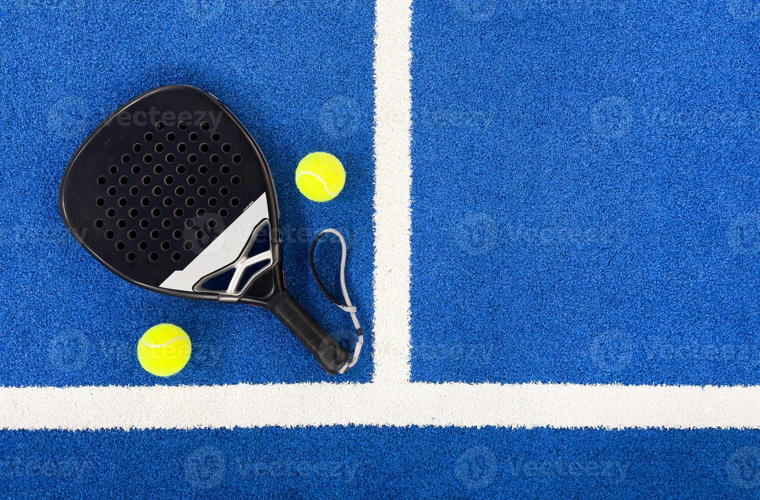 Paddle racket with a ball ready to play the fastest growing sport in recent years worldwide. Padel court in summer, the perfect time to practice this sporting discipline and release stress. photo