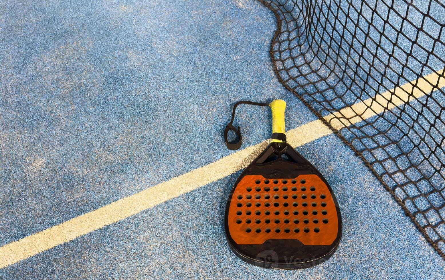 padel racket and yellow balls placed on court near net photo
