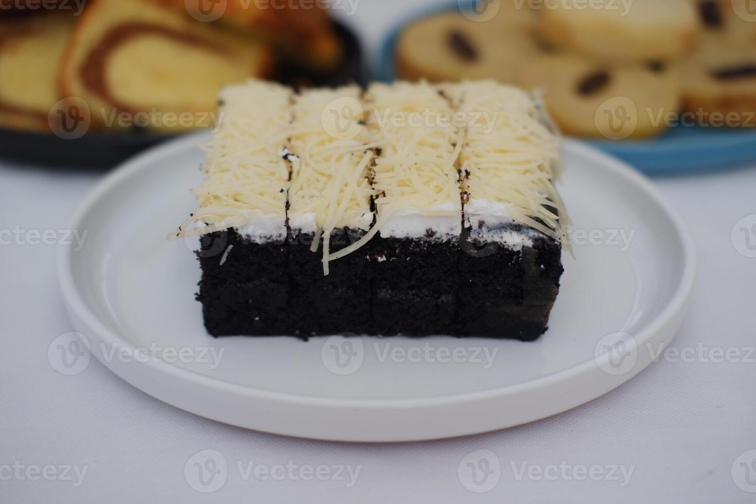 A piece of black cake topped with shredded cheese photo