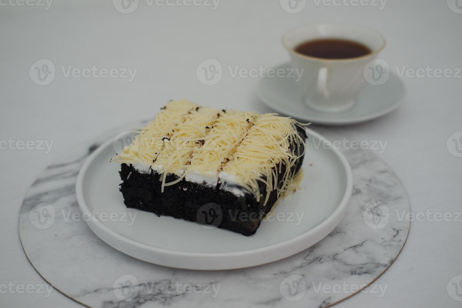A piece of black cake topped with shredded cheese photo