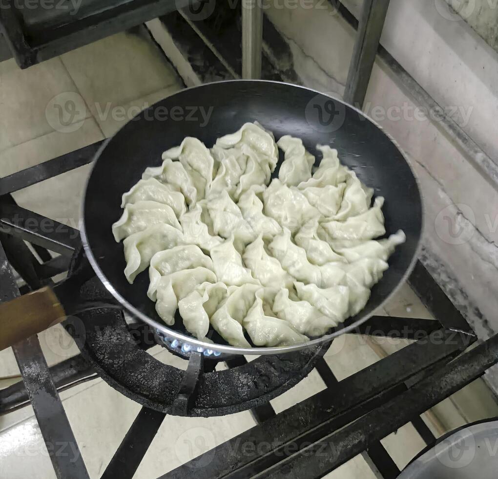 Gyoza in pan cooking on gas stove photo