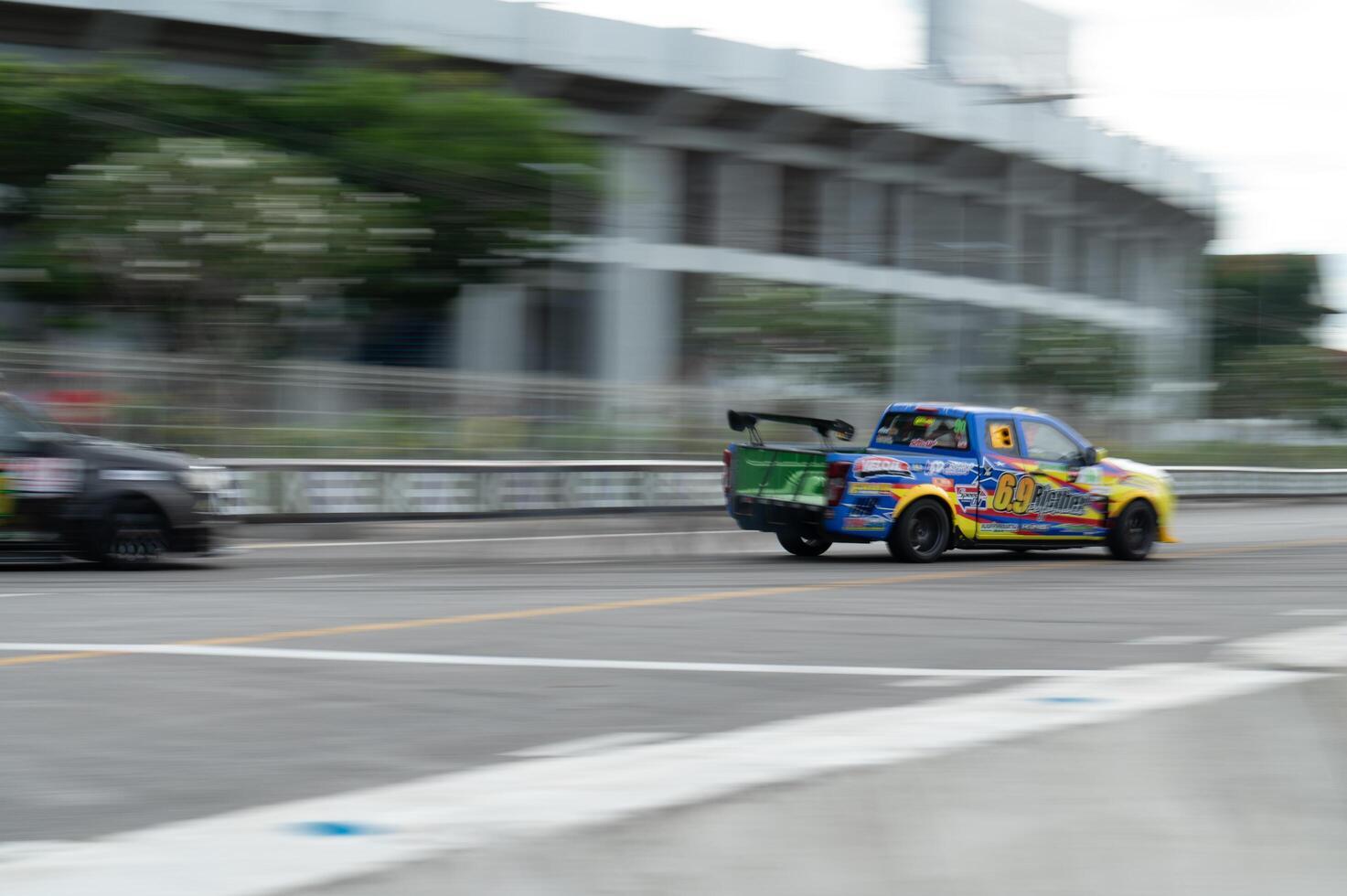 Songkhla, Moung, Thailand Oct 19, 2024 PT Maxnitron Motorsport, Dynamic shot capturing excitement of racing trucks on city street blurred motion emphasizes speed photo