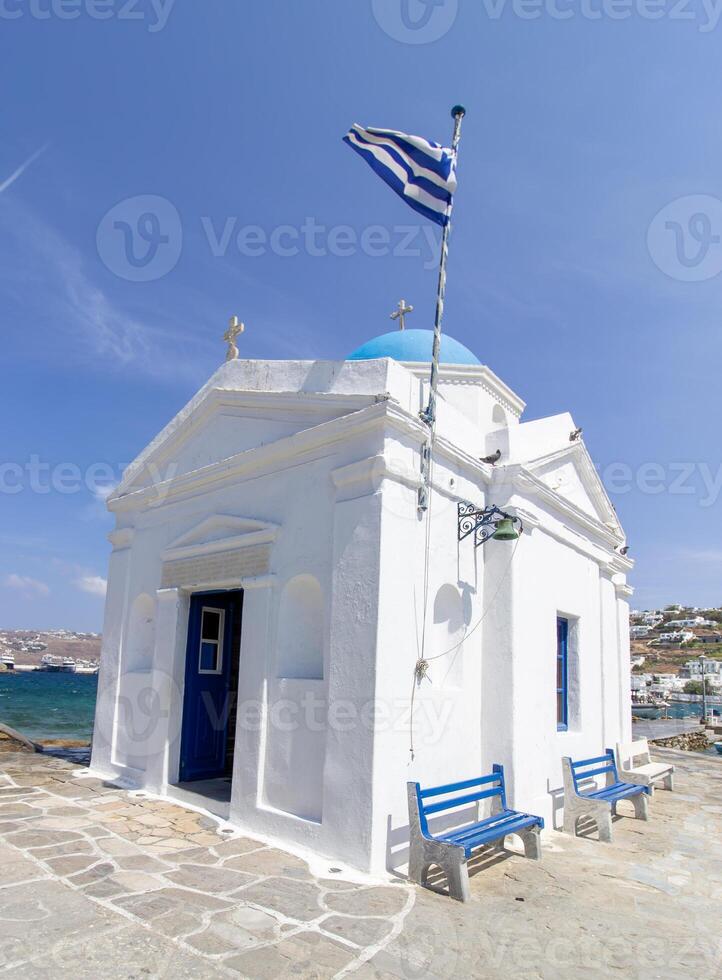 Whitewashed church in the harbor with Greece flag, Mykonos, Cyclades, Greece photo