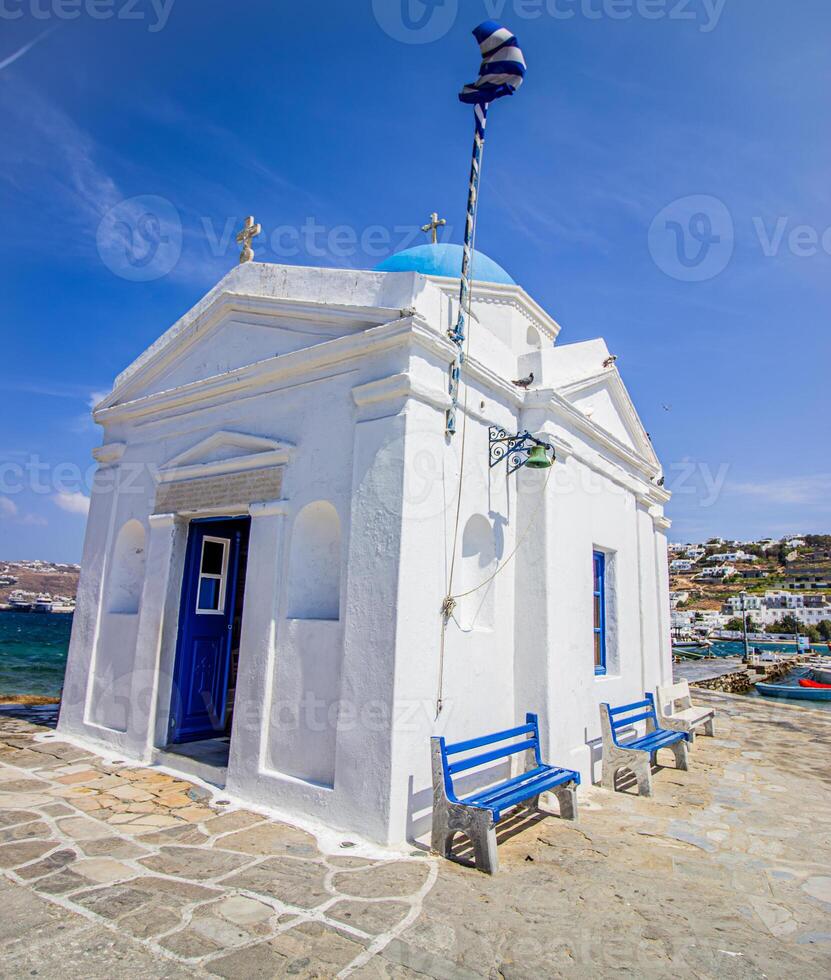 Whitewashed church in the harbor with Greece flag, Mykonos, Cyclades, Greece photo