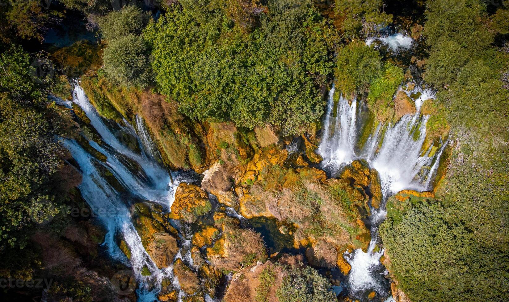 Aerial view of a small waterfall in the uncontaminated nature. Water, rocks and trees in a natural scenary. photo