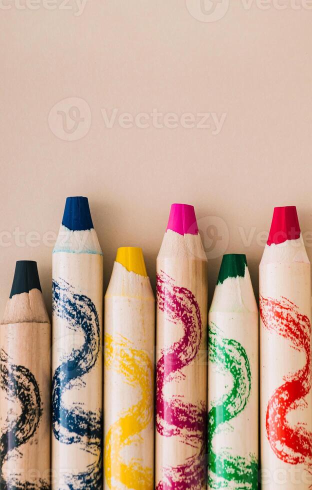Colorful wax crayons on pastel cream background. Minimal school concept. Flat lay. photo