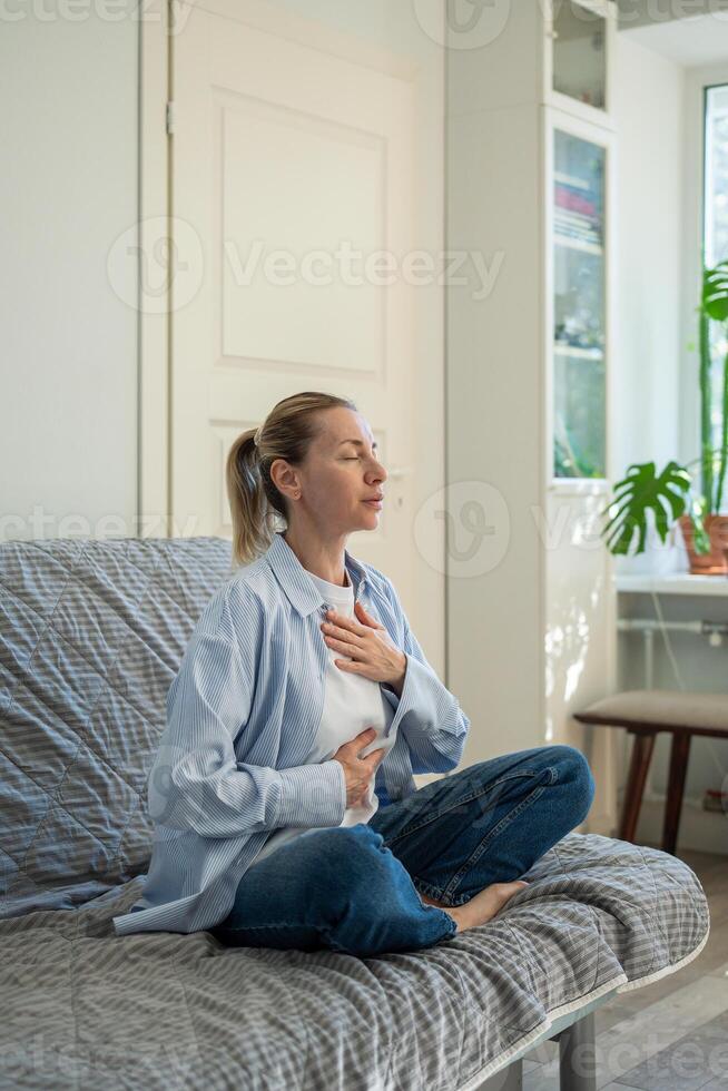 Focused woman sit cross legged on couch, practice deep breathing exercises. Yoga balance, self care photo