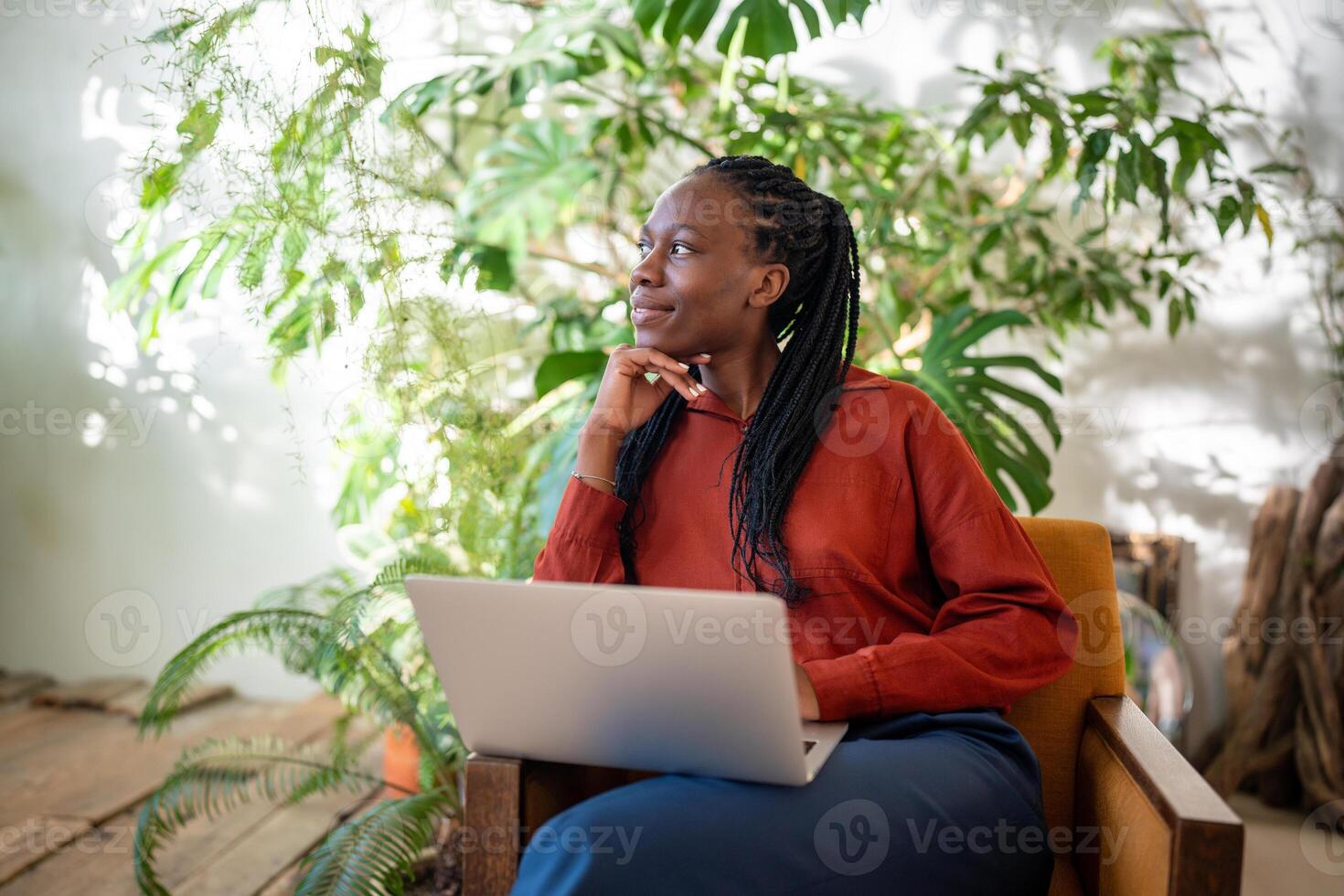 Thoughtful relaxed black woman take break from work on laptop look aside window, greenery home. photo