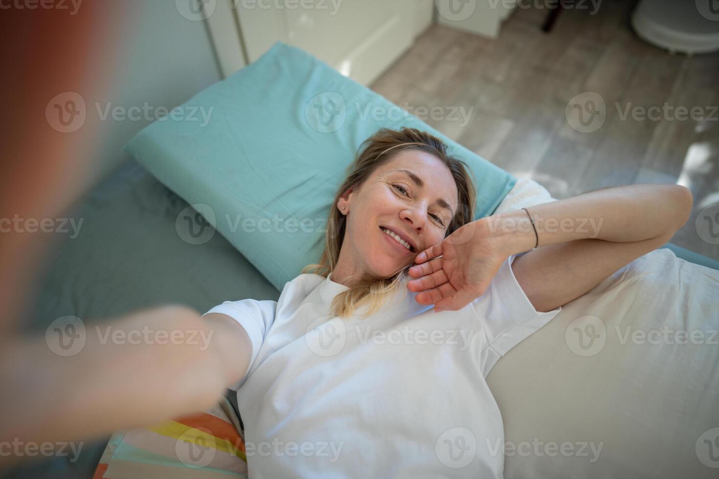 Smiling relaxed woman gently wakes up, stretching to camera. Sleep schedule, happy morning balance photo