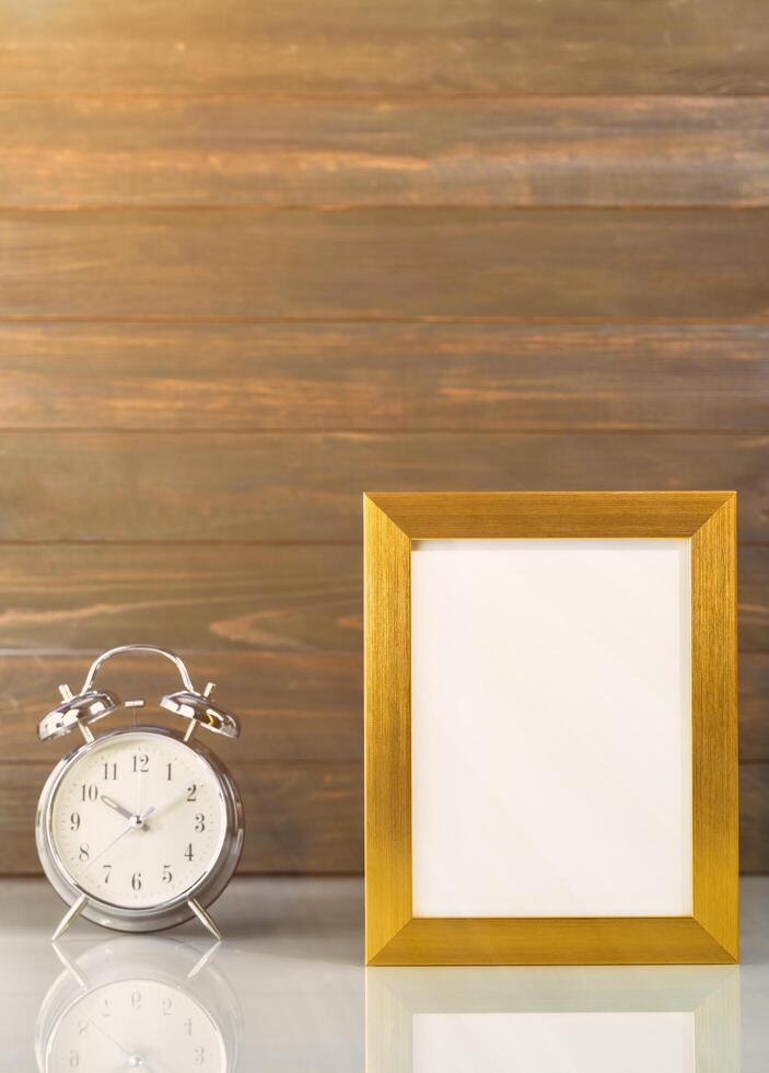 Picture mock up with golden frame and alarm clock photo
