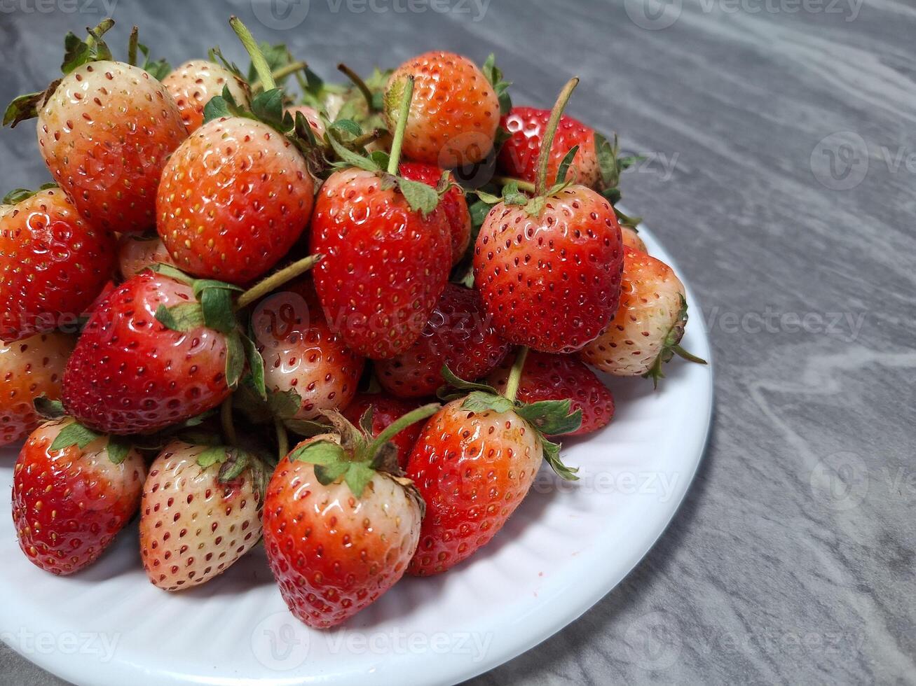 Blurred image of strawberries on a white plate placed on a table. photo