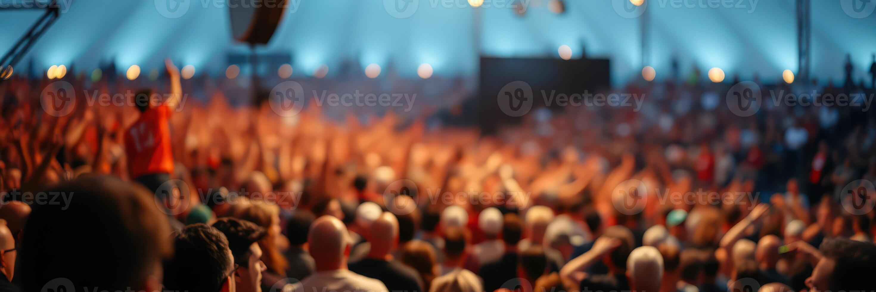Large crowd celebrates at an outdoor music festival under a tent on a warm summer evening photo