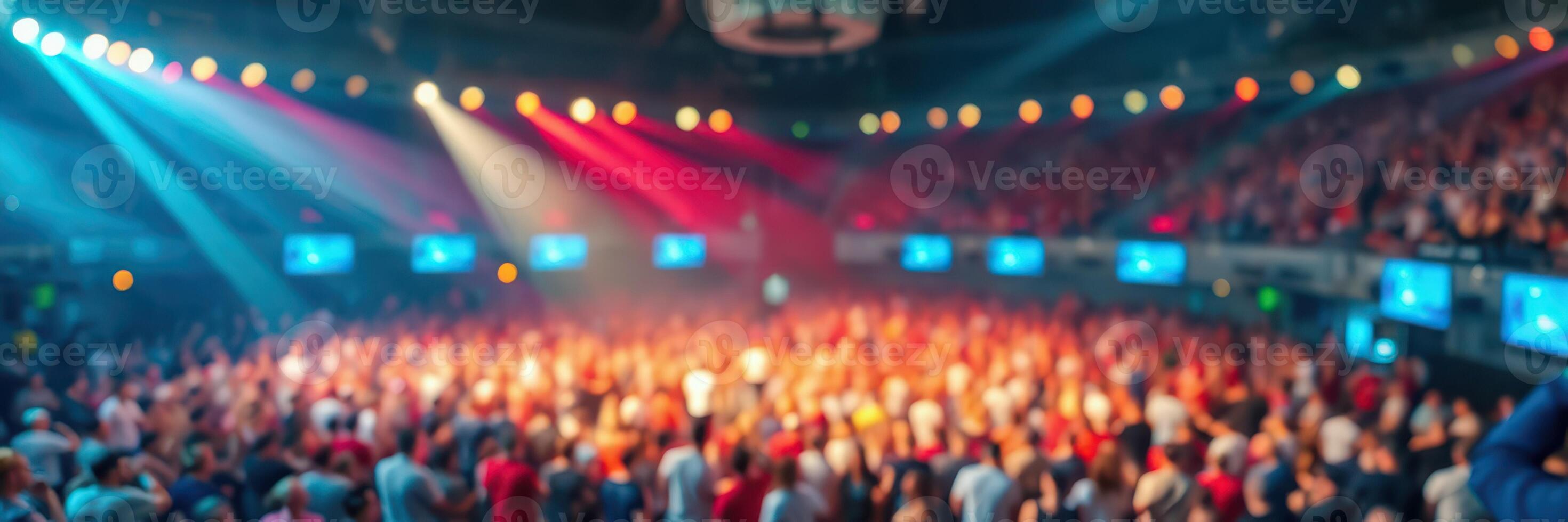 Crowd enjoying a vibrant concert with colorful lights in an indoor arena during the evening photo