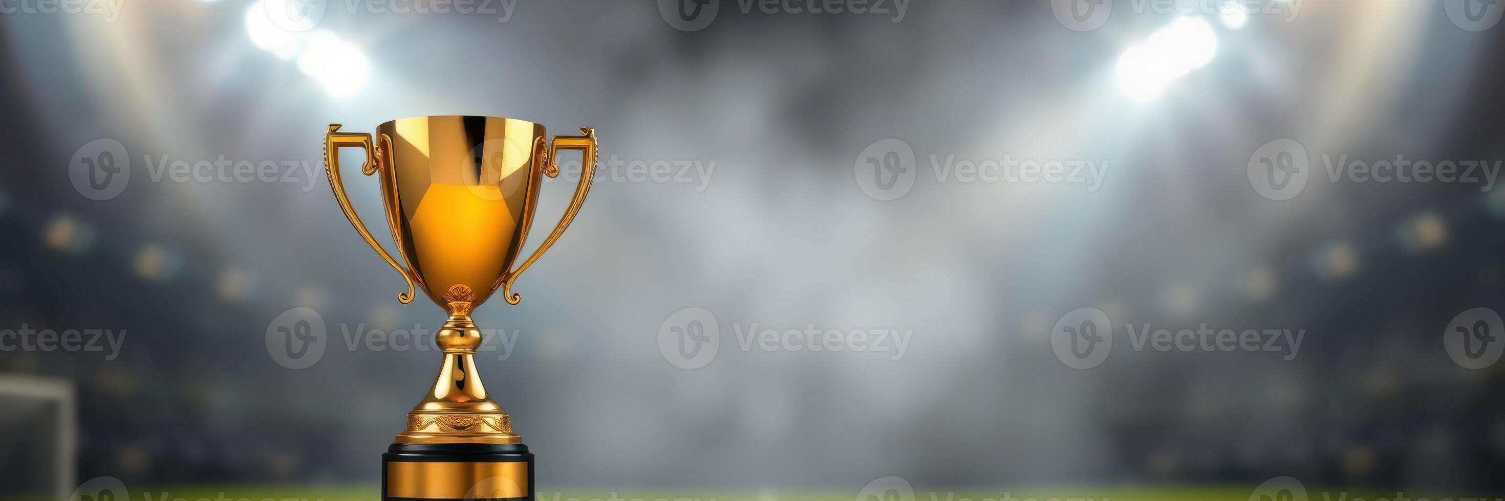 Golden trophy displayed on a blurred sports field with bright lights shining in the background during a competitive event photo
