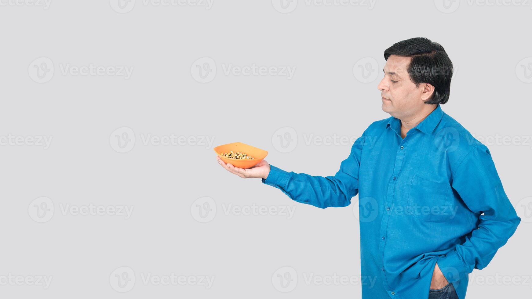 a young boy offering corn cob seeds bowl with right hand. copy space on left side photo