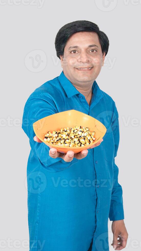 Portrait view of a front view of a young boy offering corn cob seeds bowl photo