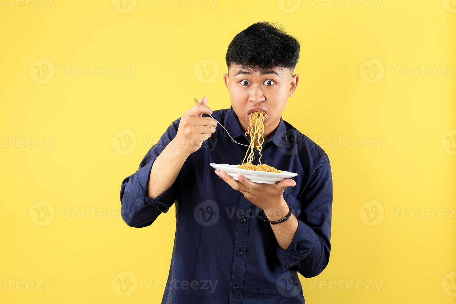 Young Indonesian Boy Wide Eyes Open, Wos Gesture While Eating Indomie Mie Goreng on White Plate photo