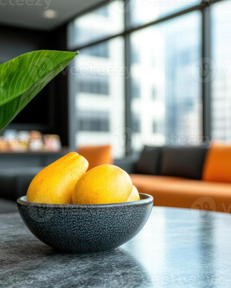 fresh yellow mangoes in a dark ceramic bowl on a kitchen counter photo