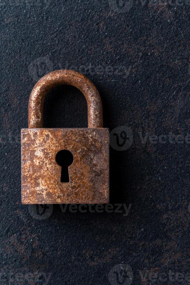 Rusty old padlock on a dark background photo