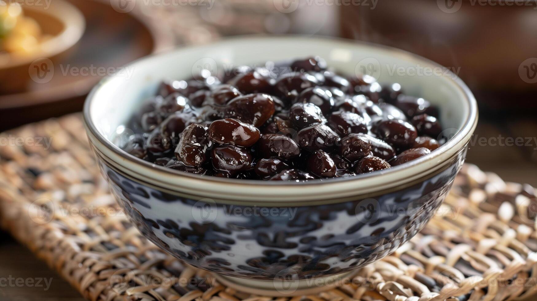 Bowl of salted fermented black beans with shiny dark surface on a woven placemat, picture photo