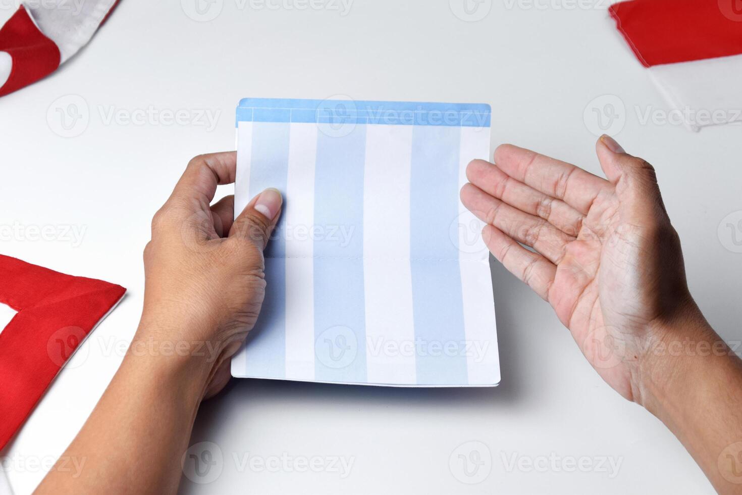A person holds and opens a savings account book with a red and white background photo