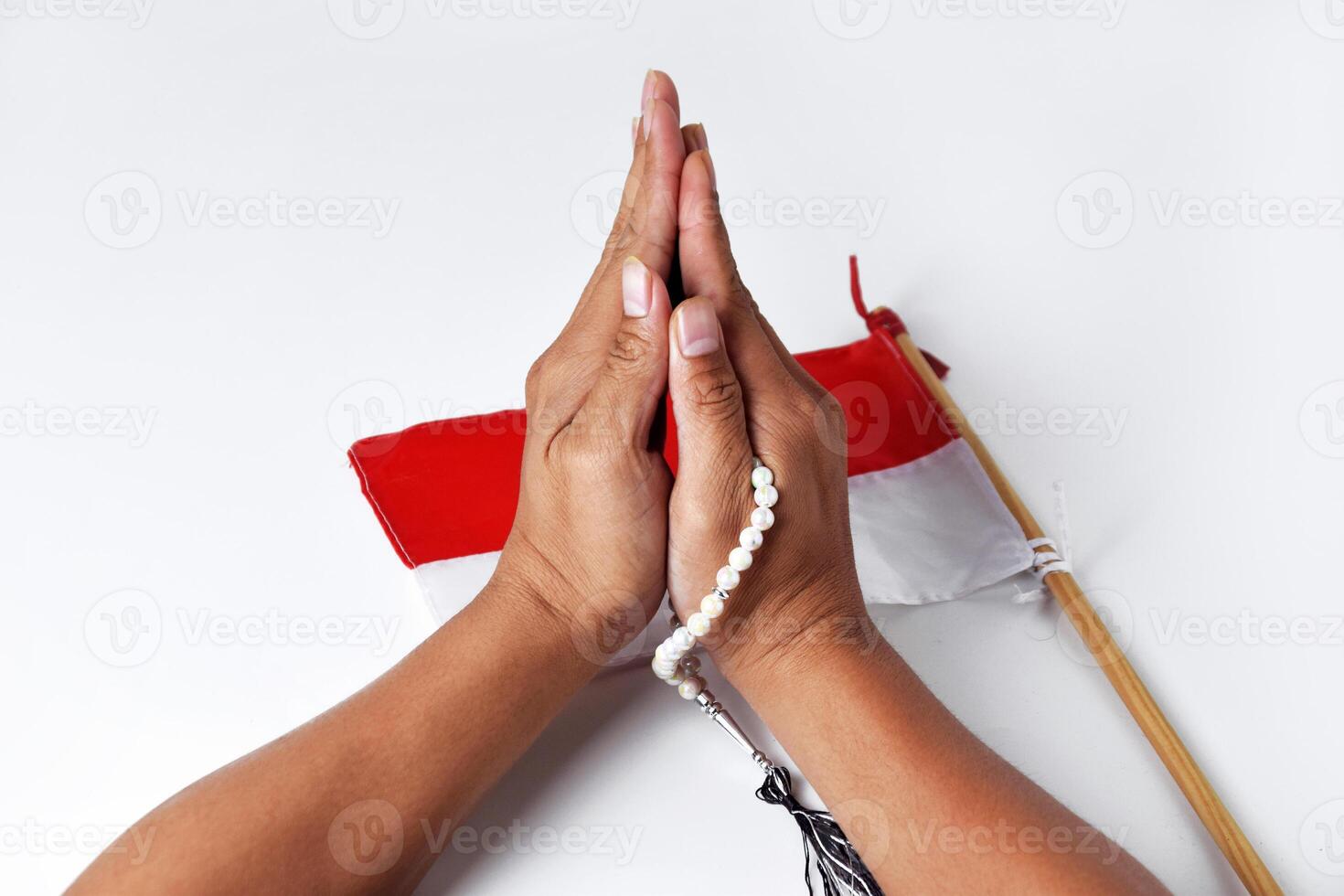 People's hands are praying using prayer beads with the red and white flag photo