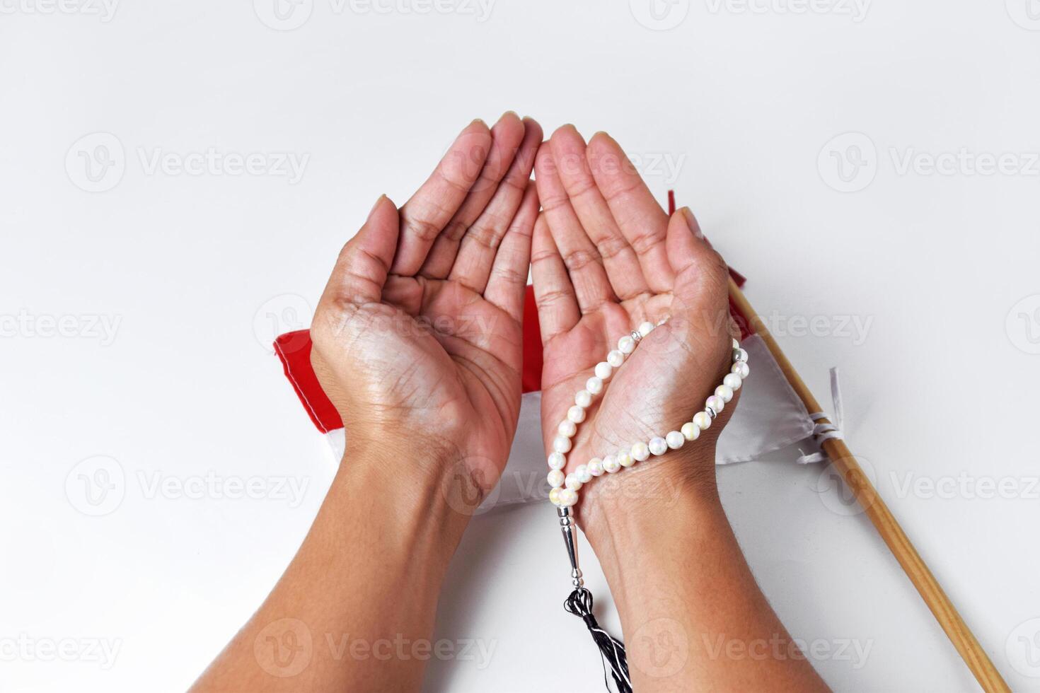 People's hands are praying using prayer beads with the red and white flag photo