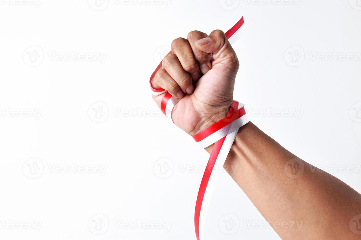 Human hands clench with red and white ribbons as symbol of the Indonesian flag photo