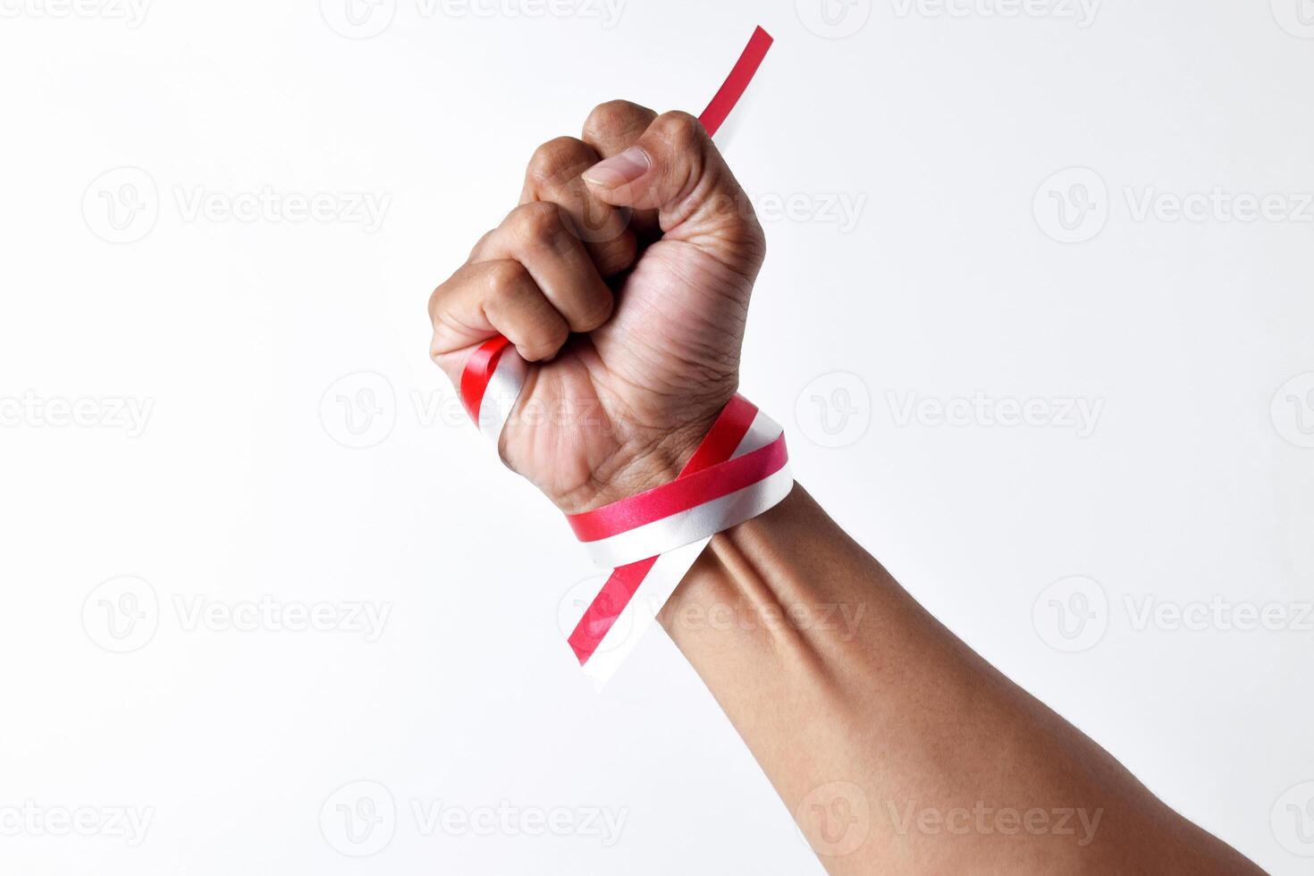 Human hands clench with red and white ribbons as symbol of the Indonesian flag photo