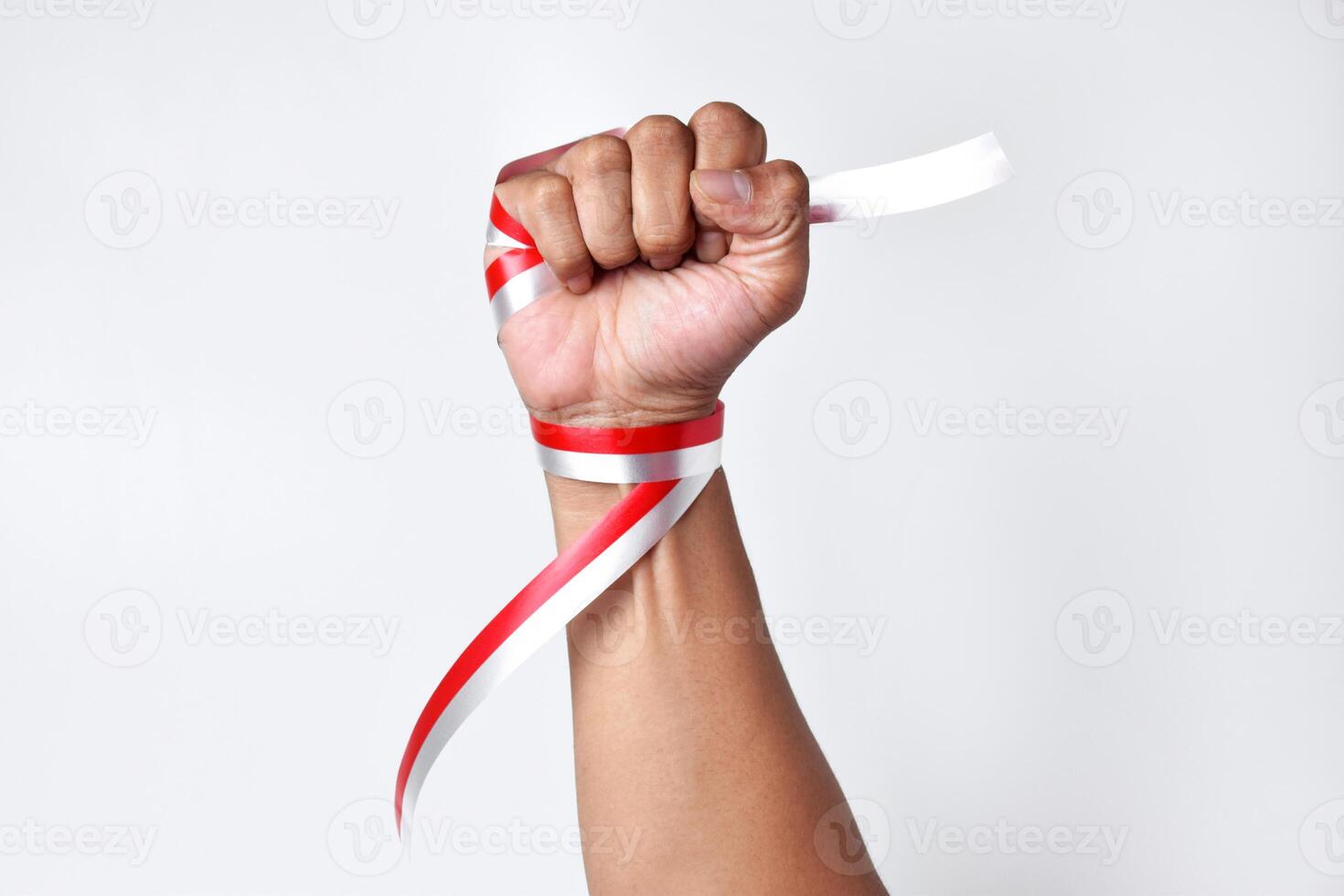 Human hands clench with red and white ribbons as symbol of the Indonesian flag photo
