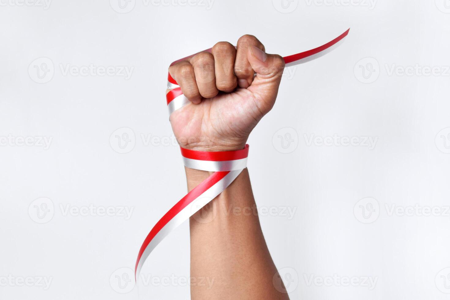 Human hands clench with red and white ribbons as symbol of the Indonesian flag photo