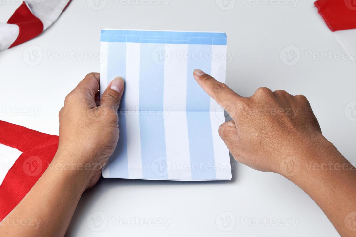A person holds and opens a savings account book with a red and white background photo