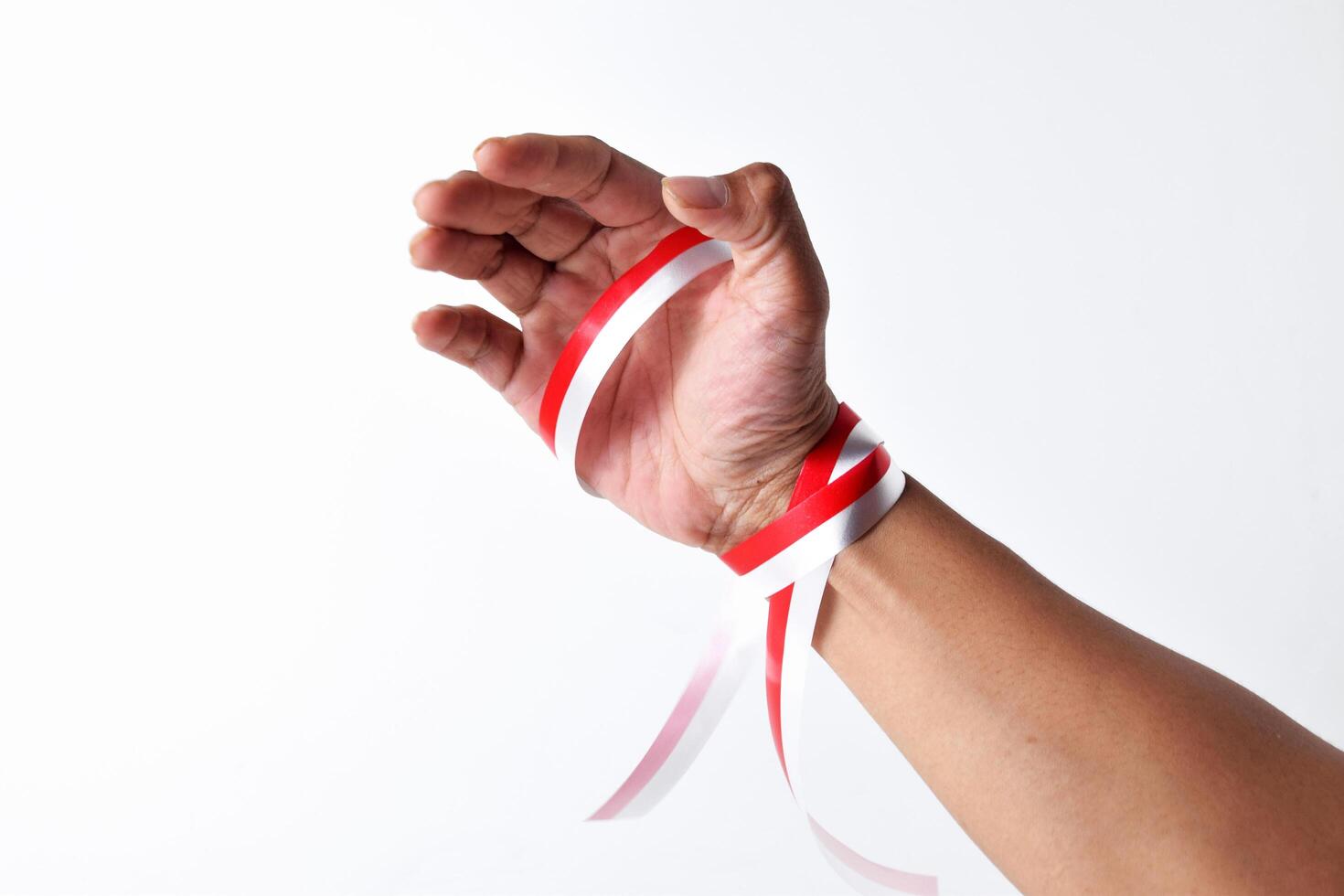 Human hands seem to be gripping the red and white ribbon photo