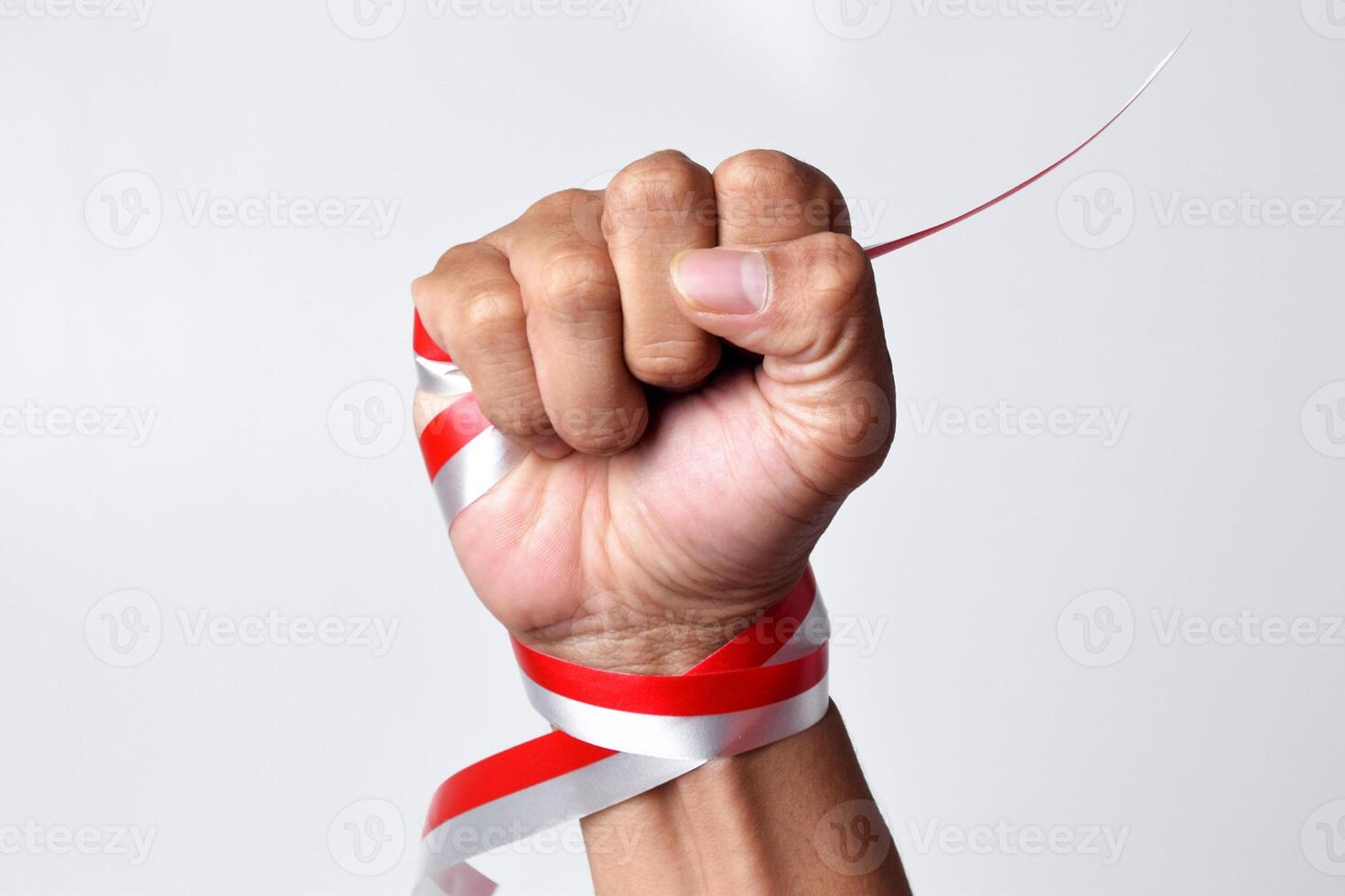 Human hands clench with red and white ribbons as symbol of the Indonesian flag photo