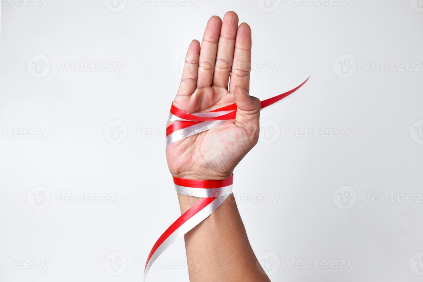 Hands spread with a red and white ribbon which is the Indonesian flag photo