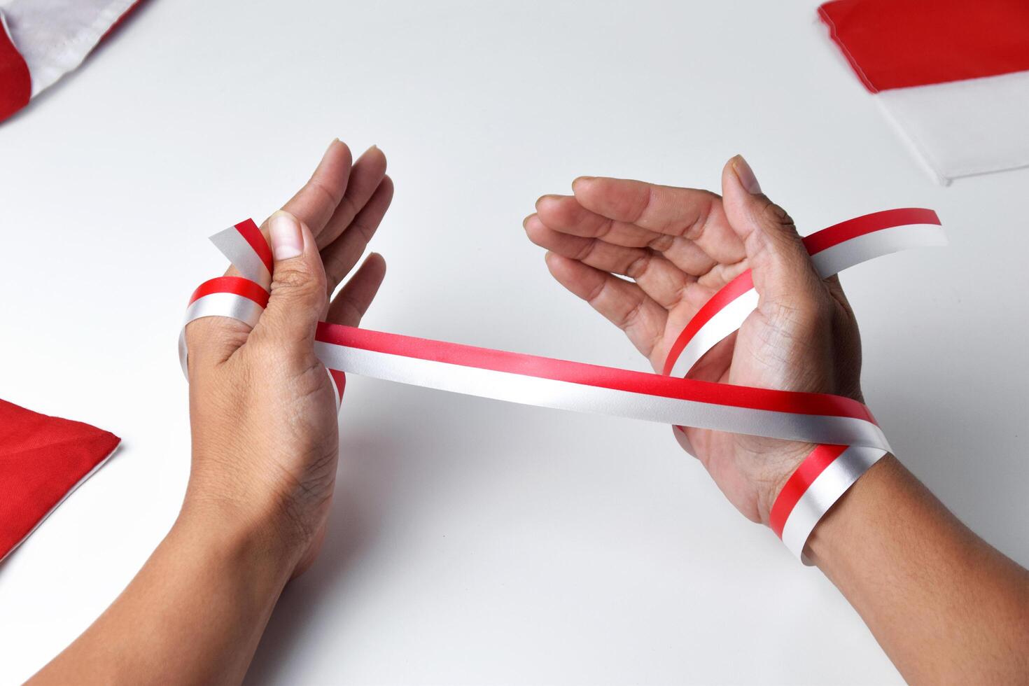 The hands of people praying are circled by a red and white ribbon photo