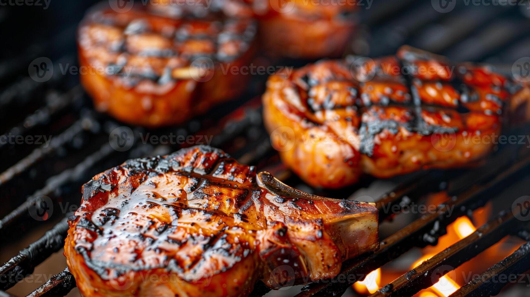 Thick pork chops searing on the grill their surfaces beautifully marked with dark grill lines and a touch of glaze, photo