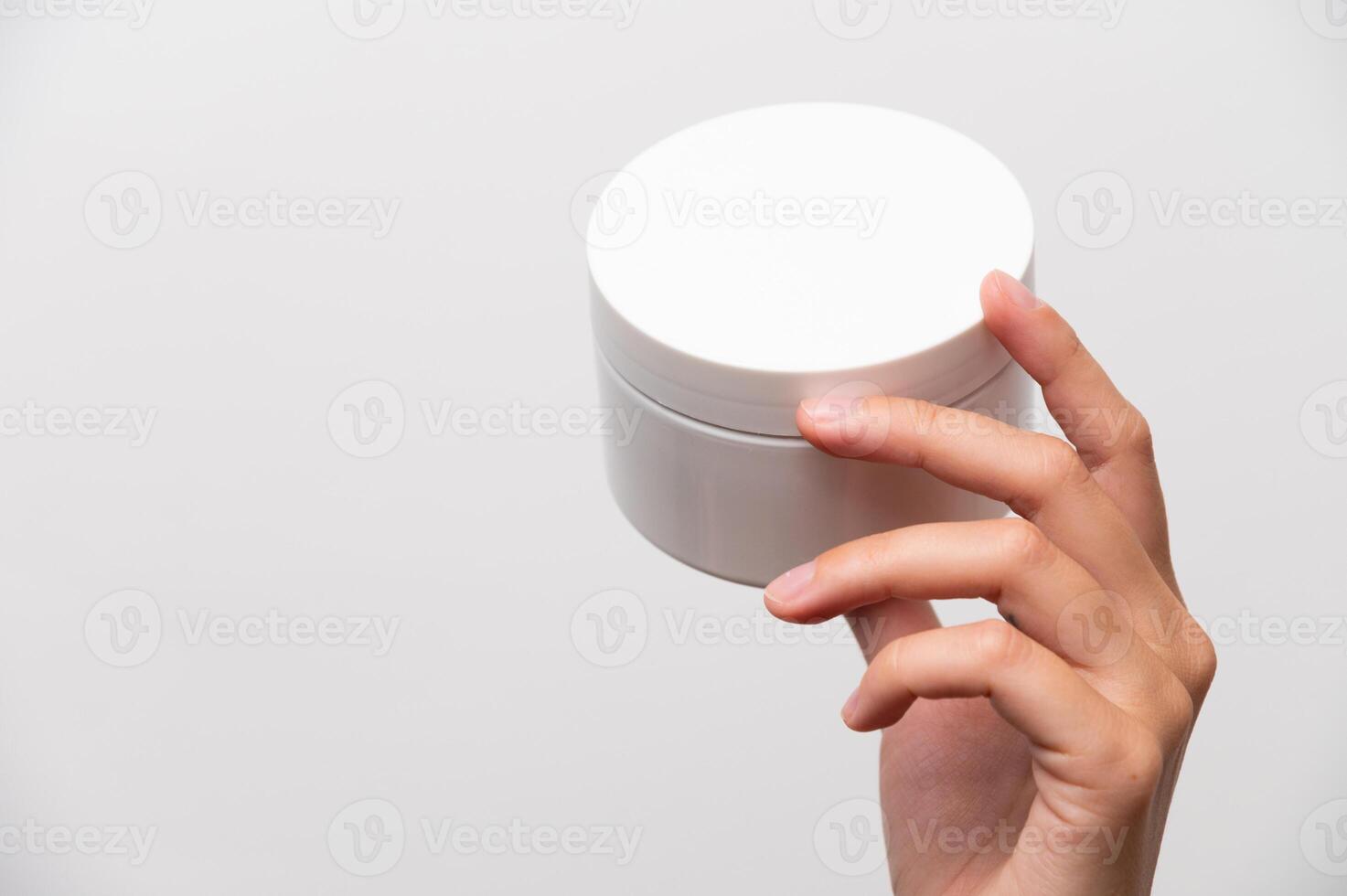 Hand hold skincare cream white bottle face cream finger on white background photo