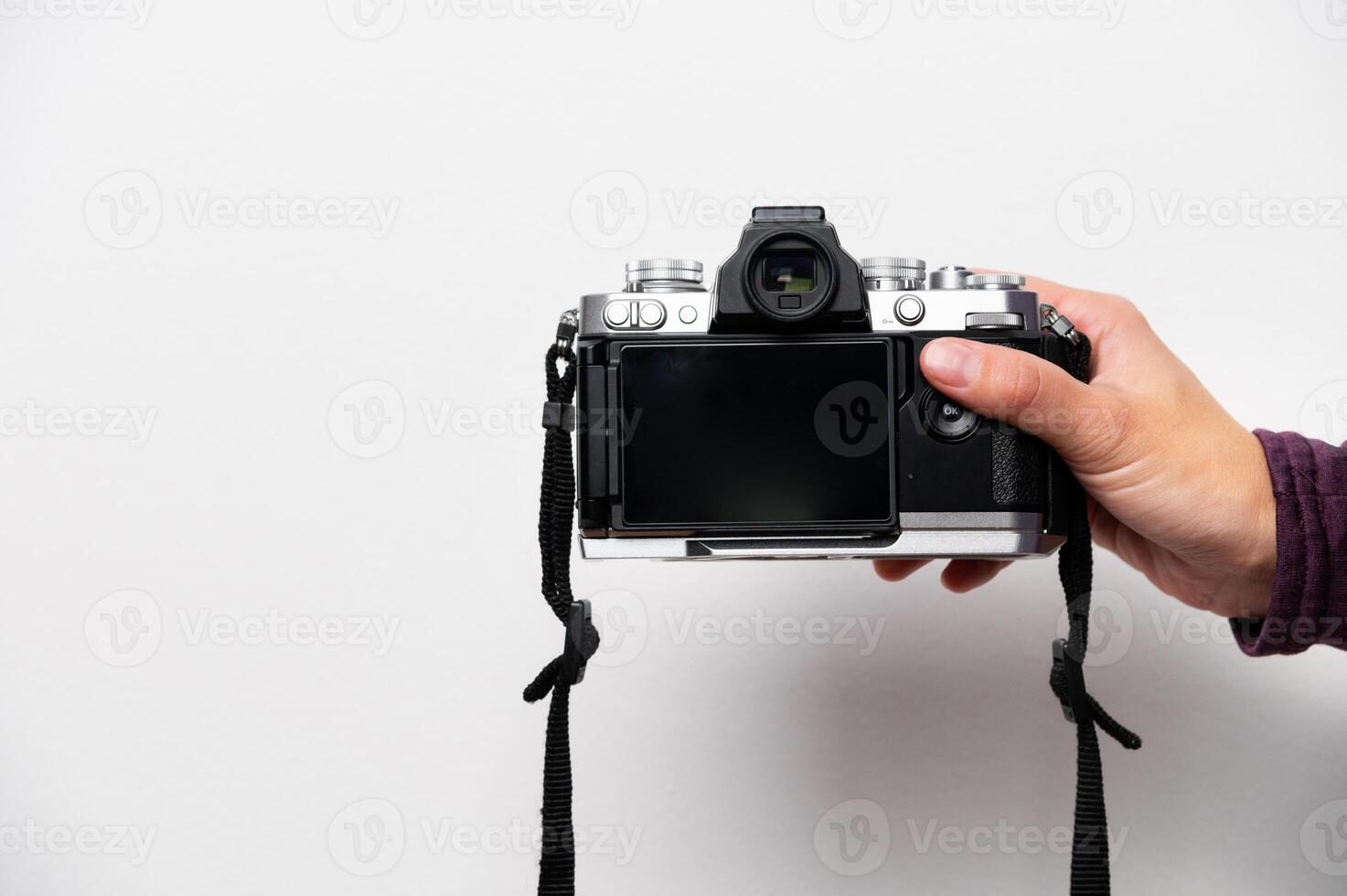 Hand holding retro camera with neck strap on white background. Vintage things, mixing old and modern style in camera design photo