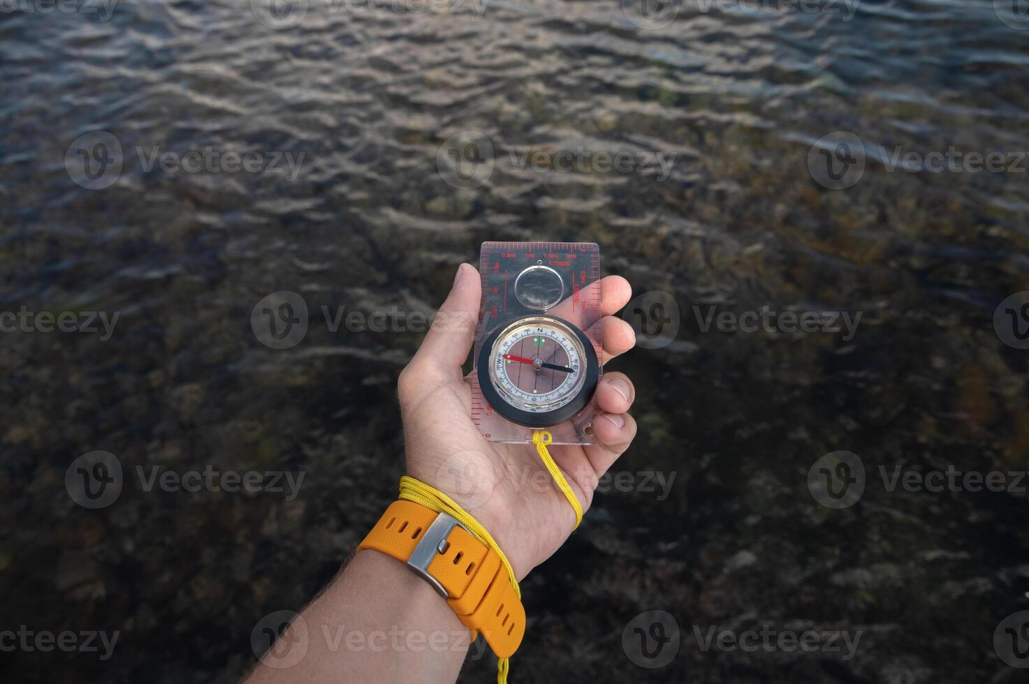 First person view of a man's hand holding a compass against a beautiful seascape. Navigation concept of finding your own way and orientation to the cardinal points photo