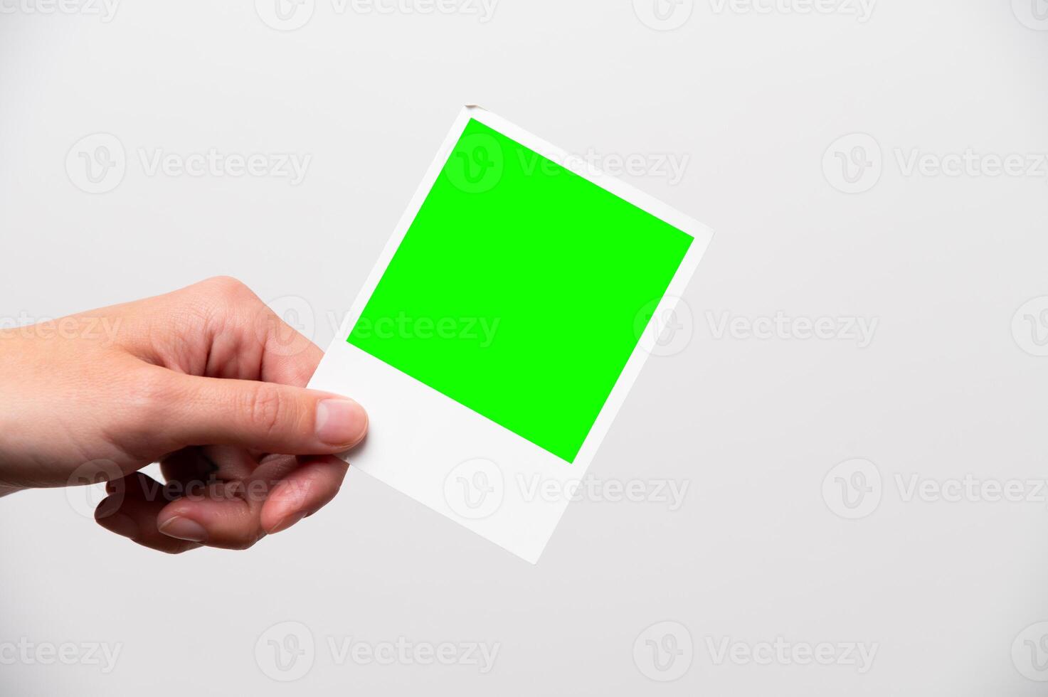 photo frame in girl's hands. instant printed photo in female hand close-up, layout for your advertising. snapshot of happy moment in life green screen
