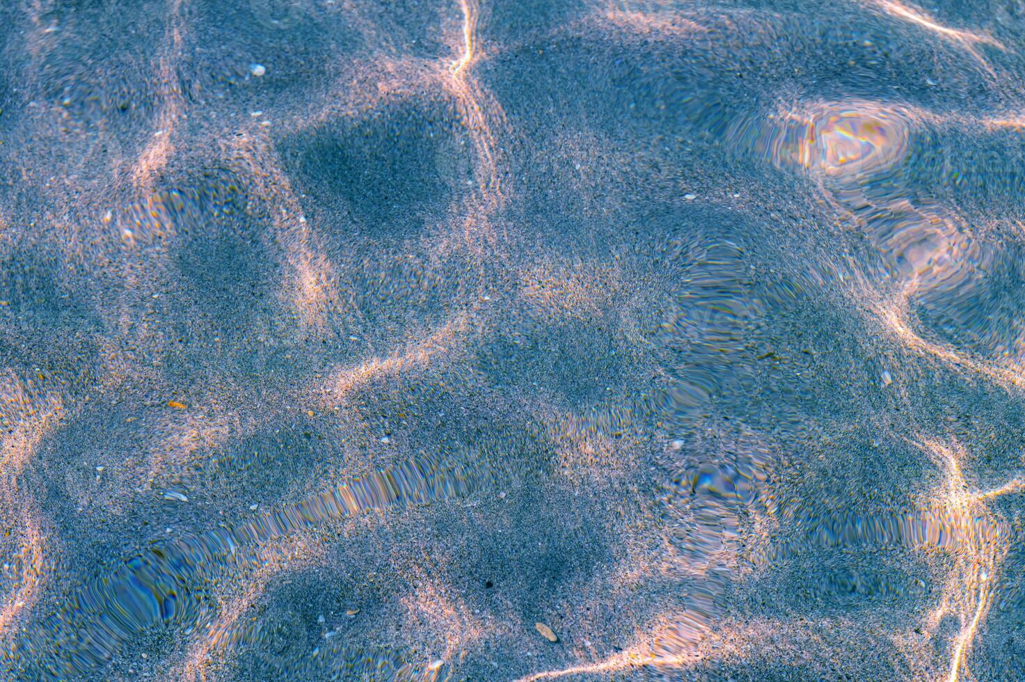 Blue Through the transparent water of the ocean or sea you can see the sandy bottom with ridges of sand. Sun glare and ripples. View from above photo