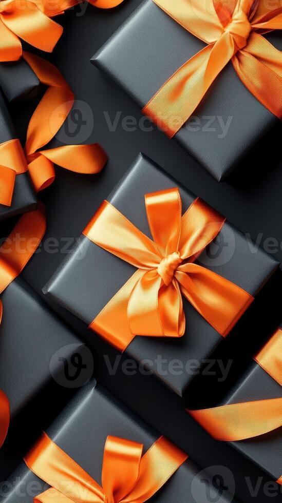 Black gift boxes with orange ribbon on black background photo