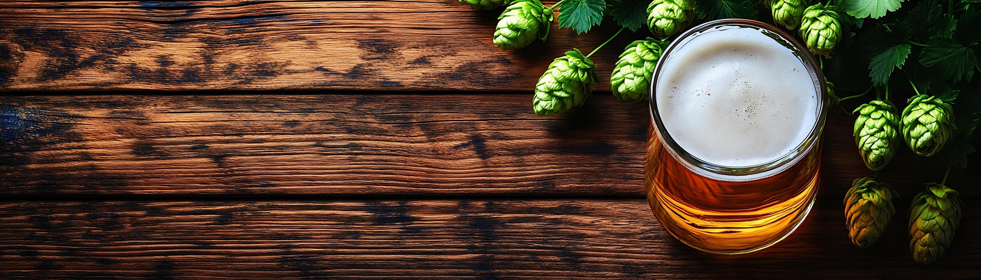A glass of beer and some hops on a wooden table photo