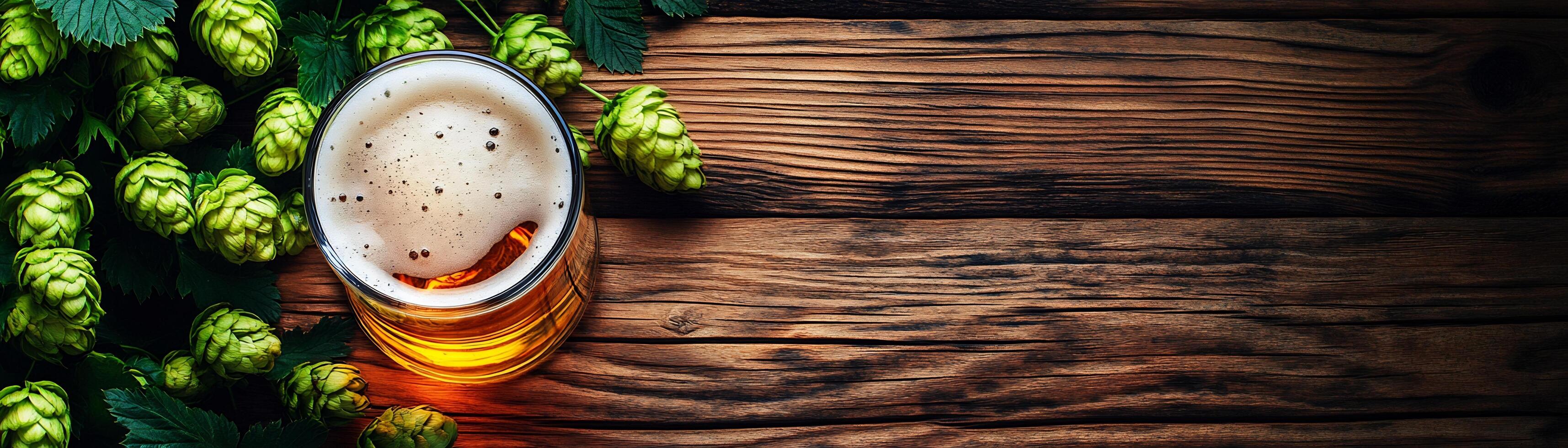 A glass of beer and hops on a wooden table photo