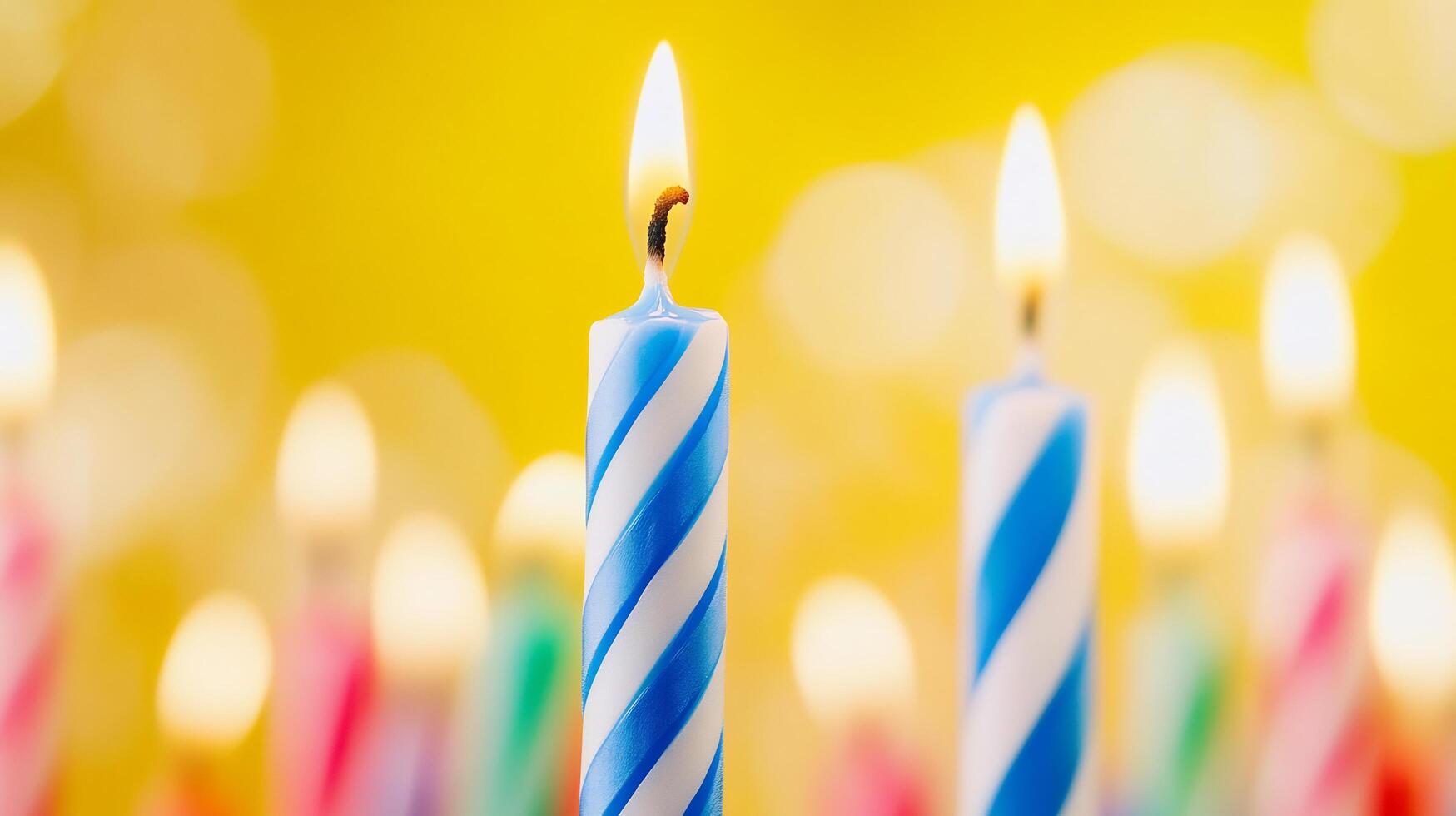 Many colorful birthday candles are lit up in front of a yellow background photo
