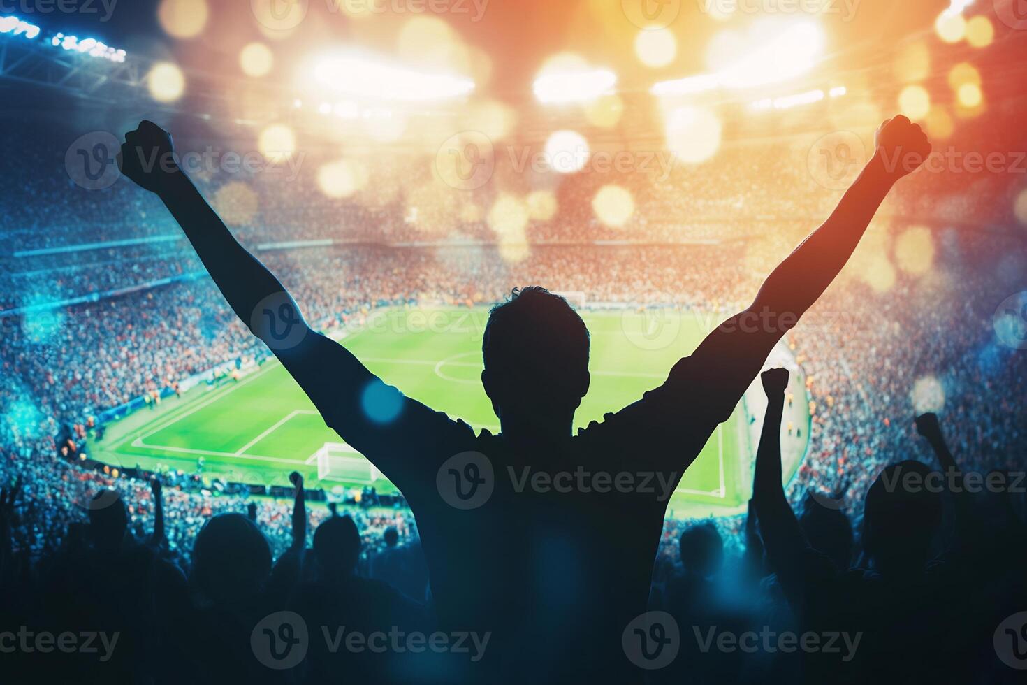 A man is raising his arms in front of a stadium photo