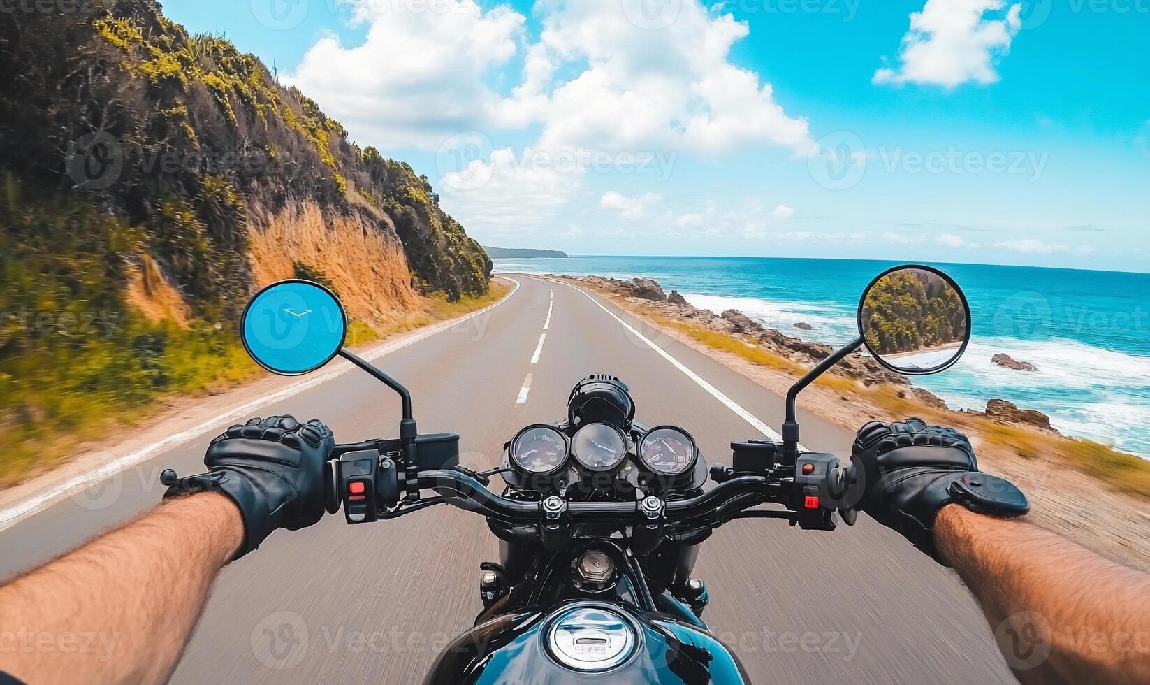 A person riding a motorcycle on a road with the ocean in the background photo