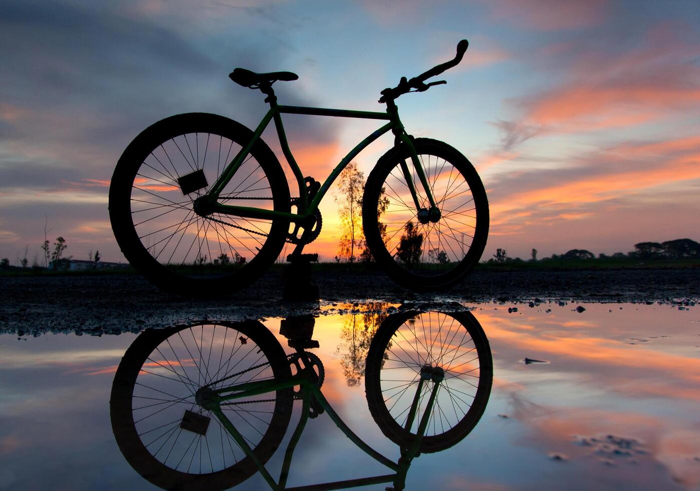 A bicycle is reflected in a puddle of water photo